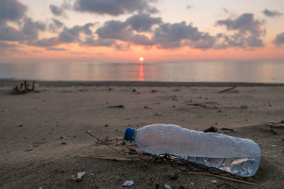 Plastic bottle pollution over sandy sea coast sunset sky, cilento italy