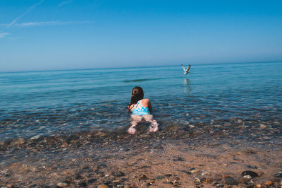 Rear view of girl lying in sea