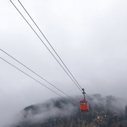 Low angle view of overhead cable car against sky