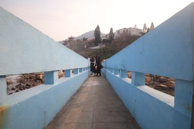 Rear view of people on wall against sky