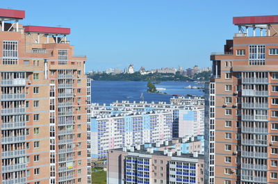 Buildings by sea against clear blue sky