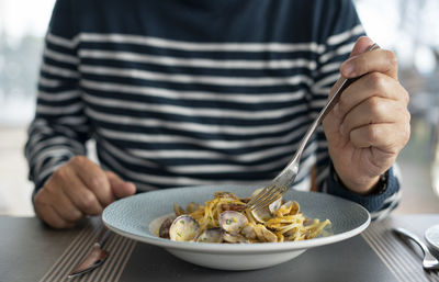 Midsection of person holding ice cream on table