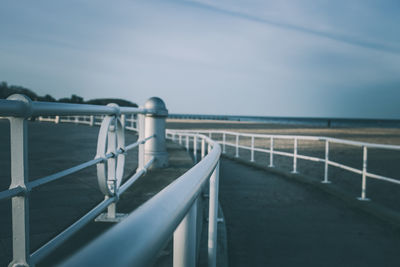 Railing by sea against sky