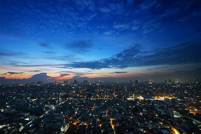 Aerial view of illuminated city against sky at sunset