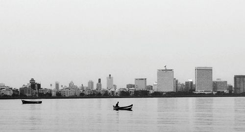 Nautical vessel on river by city against clear sky