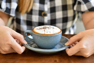 Midsection of woman holding coffee on table