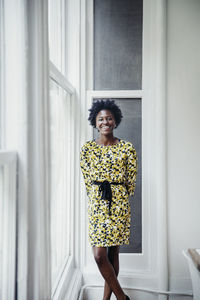 Portrait of happy businesswoman standing by window in creative office