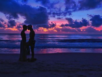 Silhouette woman standing on beach against sky during sunset