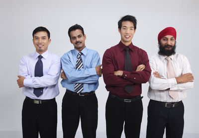 Portrait of businessmen with arms crossed standing against white background