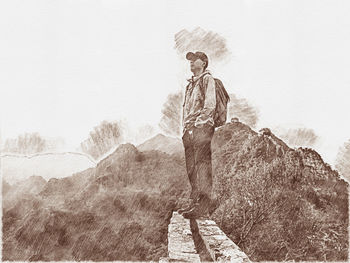Man standing on rock against sky