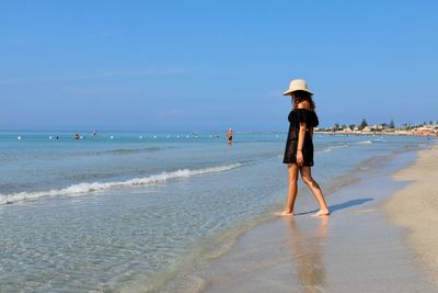 Man walking on beach against sky