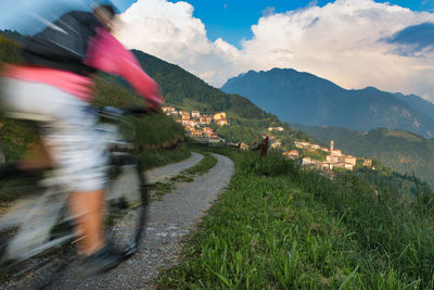 Rear view of man riding bicycle on mountain against sky