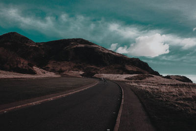 Road by mountain against sky