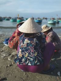 Women crouching on shore at beach