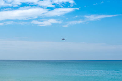 Airplane flying over sea against sky