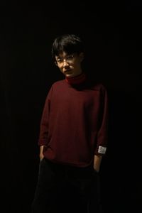 Boy standing against black background