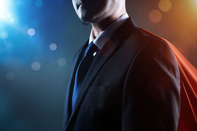 Midsection of businessman standing at illuminated nightclub