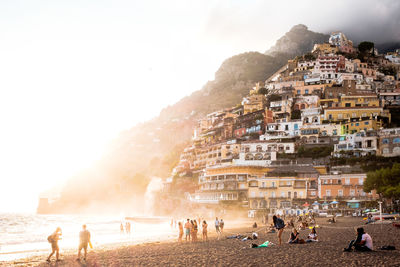 People on beach against sky in city