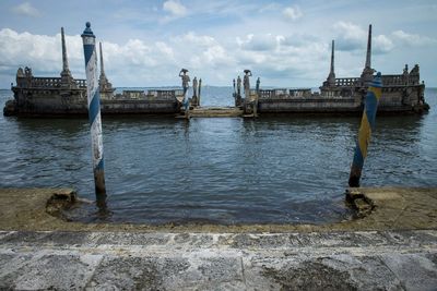 View of pier on river against cloudy sky