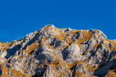 Low angle view of rock formation against clear blue sky