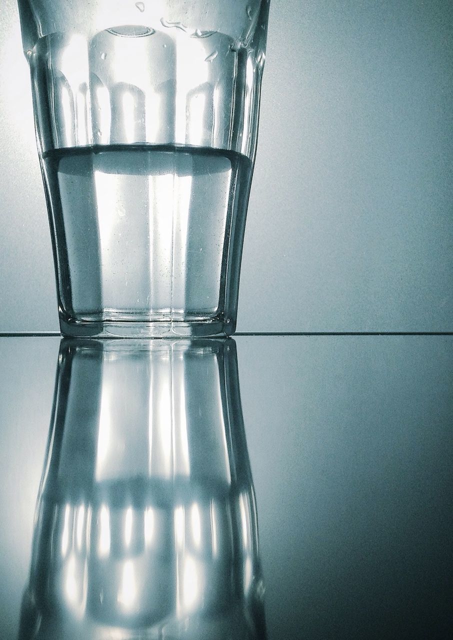 indoors, glass - material, still life, close-up, transparent, copy space, reflection, glass, studio shot, wall - building feature, no people, table, single object, white background, drinking glass, low angle view, home interior, bottle, simplicity, focus on foreground