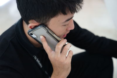 High angle view of young man talking over smart phone while sitting indoors