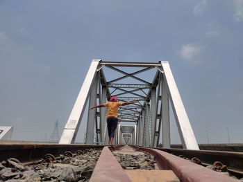 Low angle view of woman standing on bridge against sky