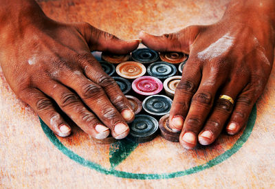 Close-up of hands around carom board coins
