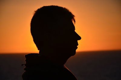 Close-up of silhouette man at beach against sky during sunset