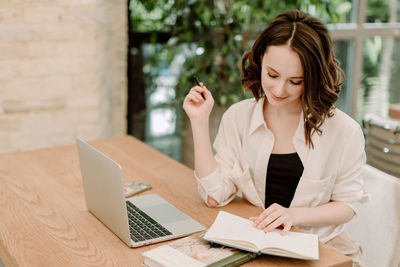 Young woman using phone while sitting on table