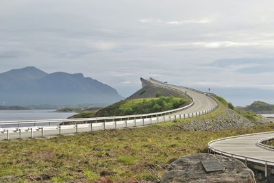 Low angle view of road against sea and mountains