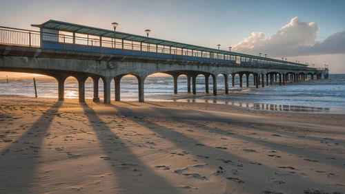 Bridge over sea against sky during sunset
