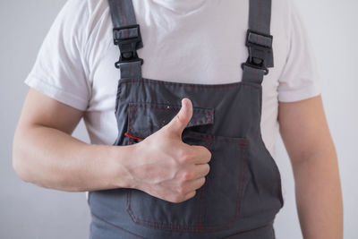 Impersonal worker in overalls showing thumbs up