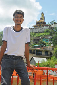 A handsome guy smiling posing by lake and beautiful hilly area of tso-pema.