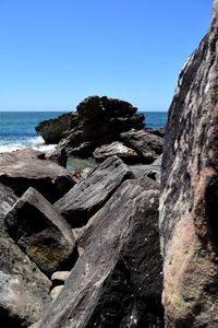 Rocks on beach against clear sky