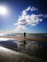 Silhouette man standing on beach against sky