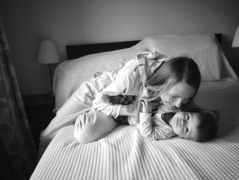 Woman playing with son on bed at home