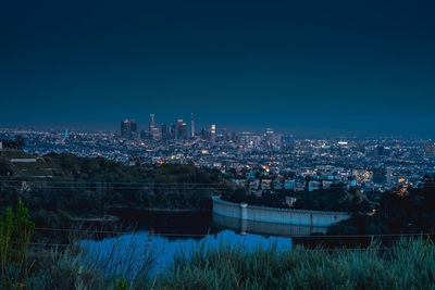 Illuminated buildings in city against clear sky at night