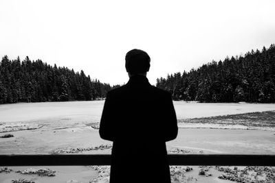 Rear view of man standing on snow covered field