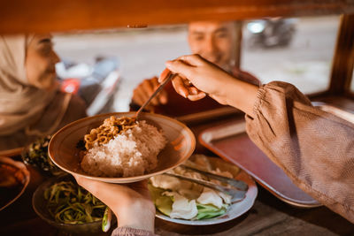 Cropped hands of woman holding meal in plate