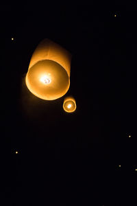Low angle view of illuminated lantern against dark sky