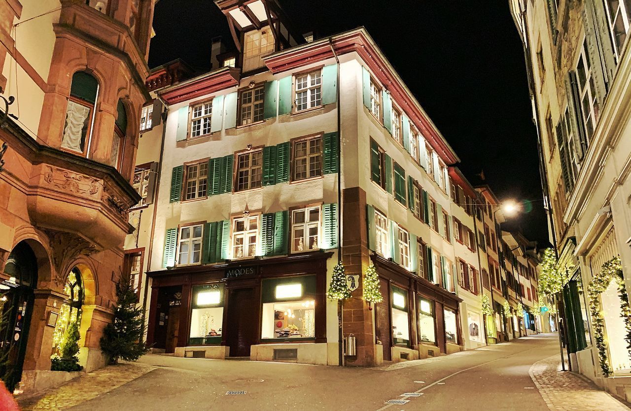 STREET AMIDST BUILDINGS AGAINST SKY AT NIGHT