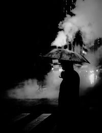 Rear view of silhouette woman standing against sky at night