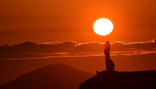 Silhouette person standing against sky during sunset