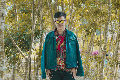 Portrait of young man standing against trees