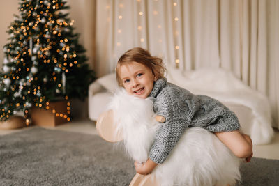 Little girl child in knitted sweater having fun playing christmas holiday in decorated house