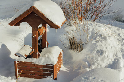 Winter village landscape. wooden well with a winch in the snowdrifts