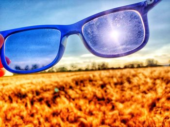 Close-up of sunglasses on field against sky