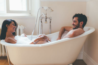 Smiling couple sitting in bathtub