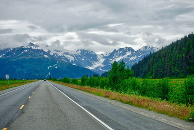 Road by mountains against sky